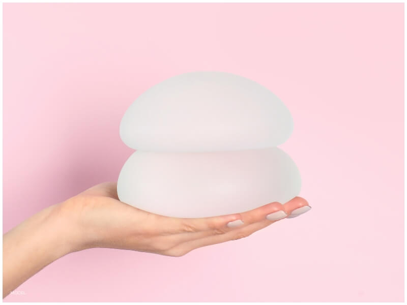 patient holding breast implants weighing out options and considering implant sizing process