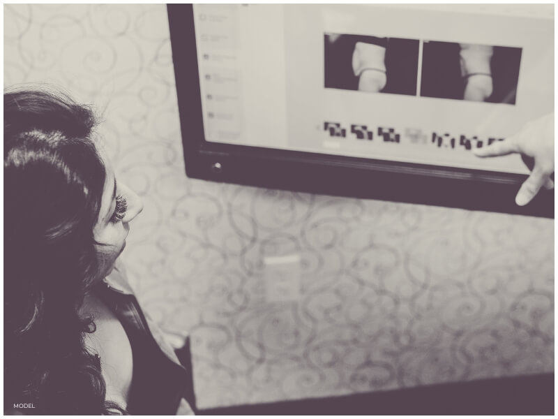 woman in plastic surgery office reviewing before and after photos showing the importance of taking photos